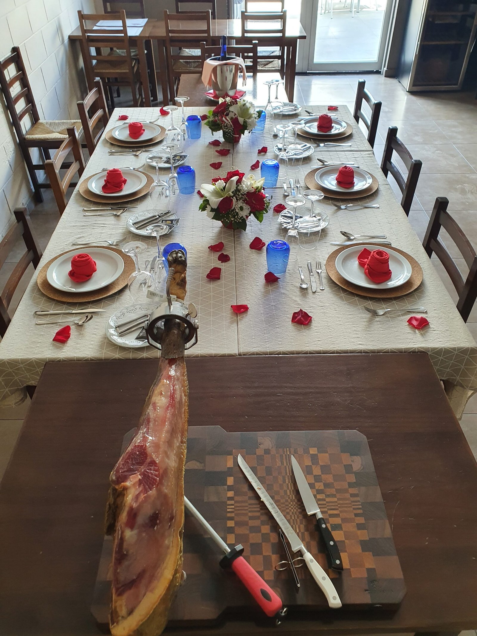 Mesa larga preparada en el salón, con un jamón en primer plano