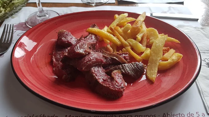Carne a la brasa cortada, servida con patatas fritas